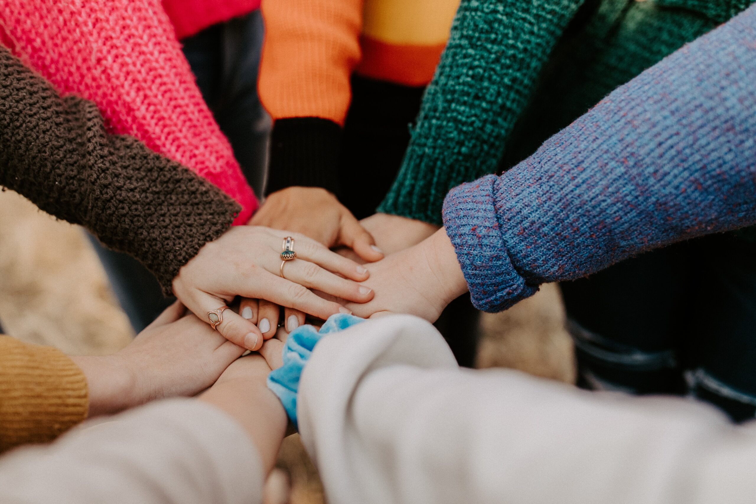 A group of eight people hold their hands out together in a circle 