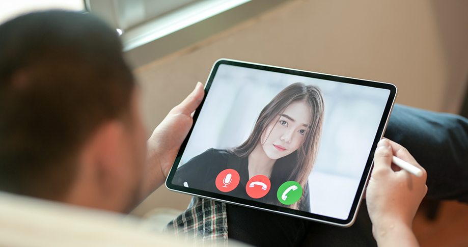 Person holding ipad with person's face on video call for remote interview