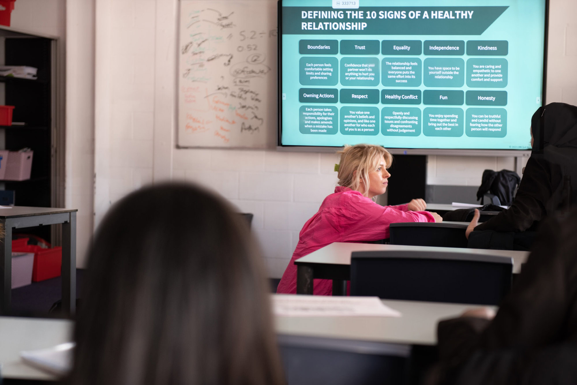 Woman leans forward on a desk in front of a screen with information about the 10 signs of a healthy relationship