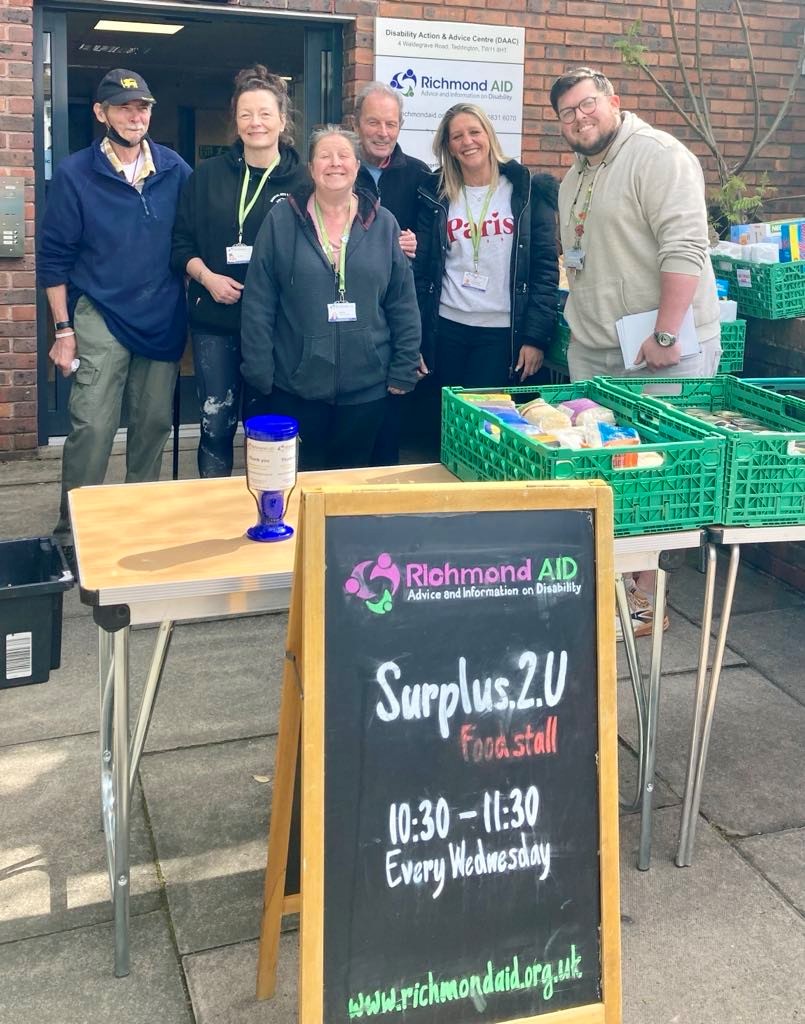 Volunteers gather behind Surplus.2.U market stall